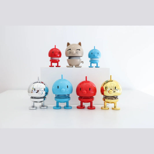 A vibrant Hoptimist bobblehead, the Classic Bumble, stands on a clean surface. The figure is a harmonious, round shape with a cheerful smile.